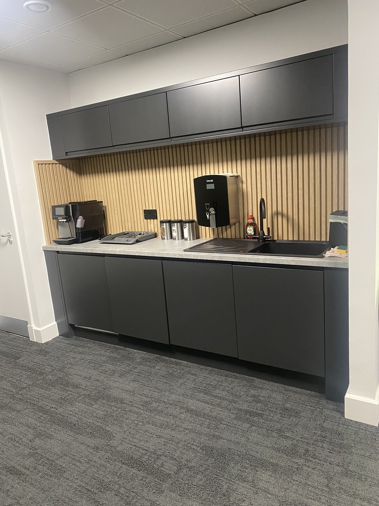 Office refreshment area with dark cabinets, a sink and drinks facilities
